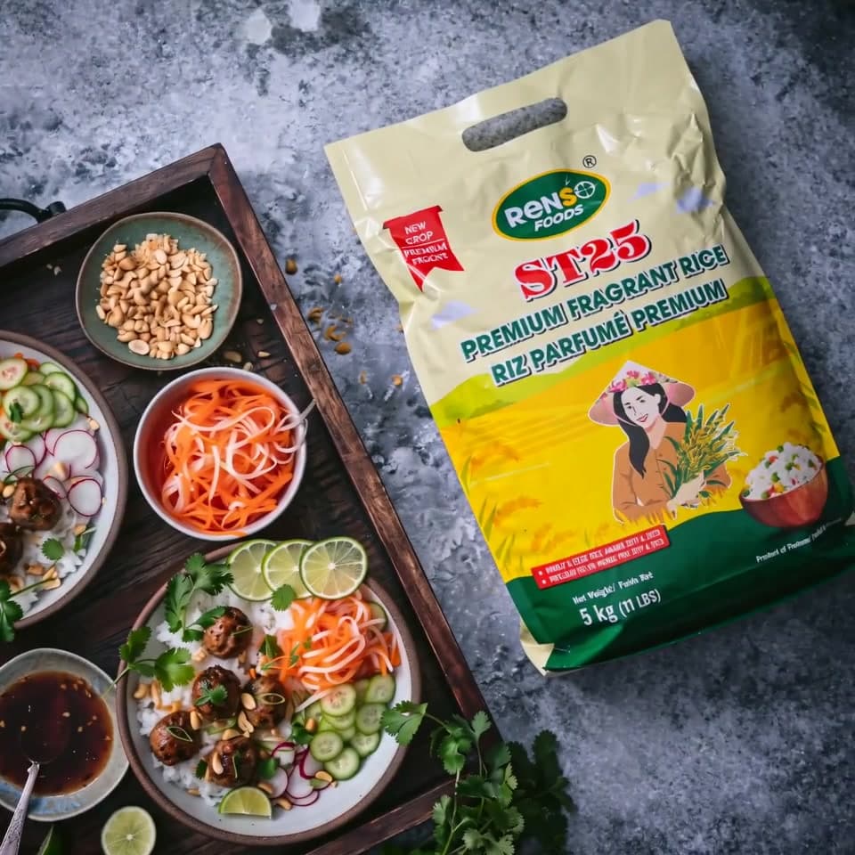 A Vietnamese meatball rice bowl spread on a wooden tray beside a bag of Renso ST25 fragrant rice
